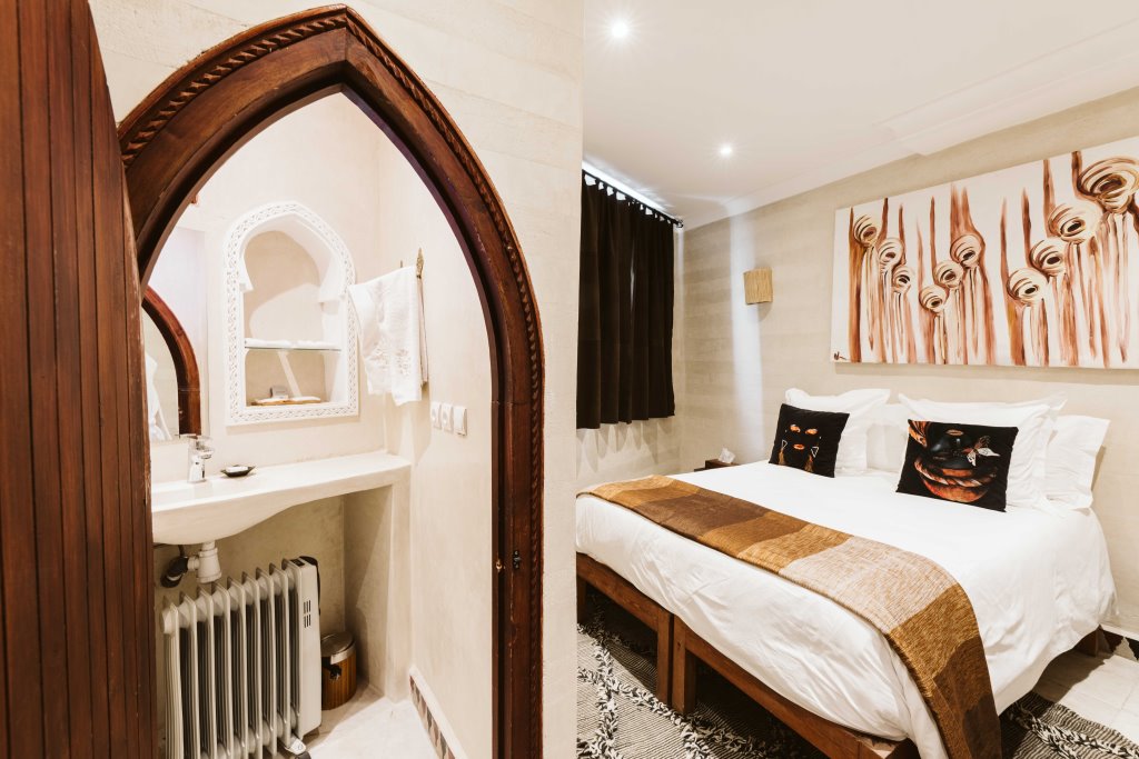 Limoni Room, a vibrant orange and white room with hand-carved wood, Riad Dar Alhambra Marrakech